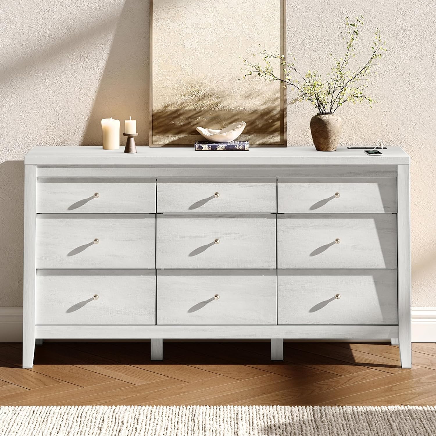 White dresser with decorative items on a wooden floor and beige wall.
